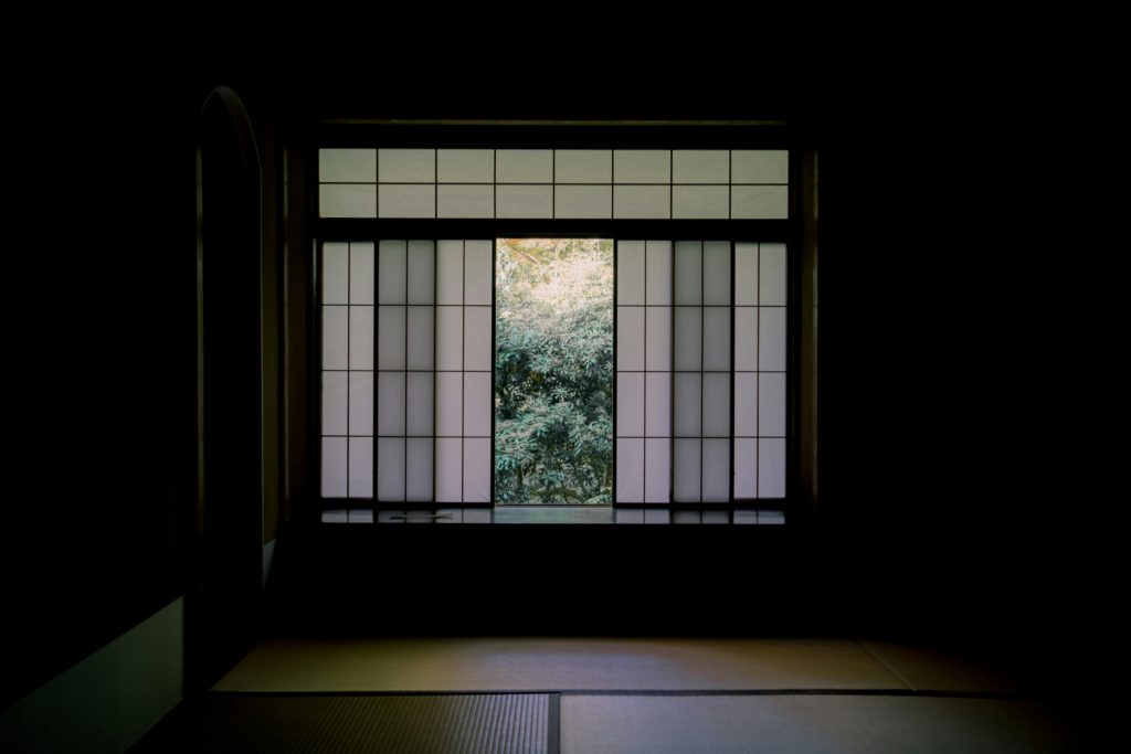 Serene view from a Japanese room through a shoji window to a tranquil garden.