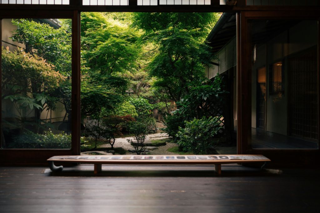 A serene view of a lush Japanese garden from a traditional Kyoto home, capturing natural beauty and cultural elegance.